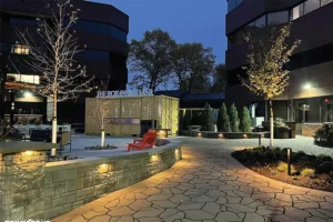 Outdoor commercial space with illuminated walkway and modern architecture at dusk, featuring landscaping and a decorative structure labeled 'THE BOX OF BRAEMAR