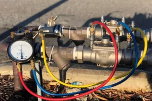 Irrigation backflow prevention device with pressure gauge and color-coded hoses used for backflow testing and maintenance.