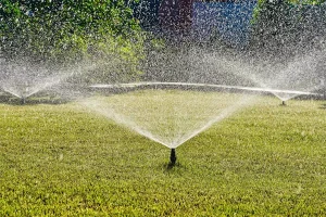 Lawn sprinkler system spraying water across green grass for irrigation and landscape maintenance in Raleigh, NC