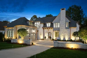 Luxury home in Raleigh, NC with architectural outdoor lighting highlighting stone walls, entryway, and landscaping at night