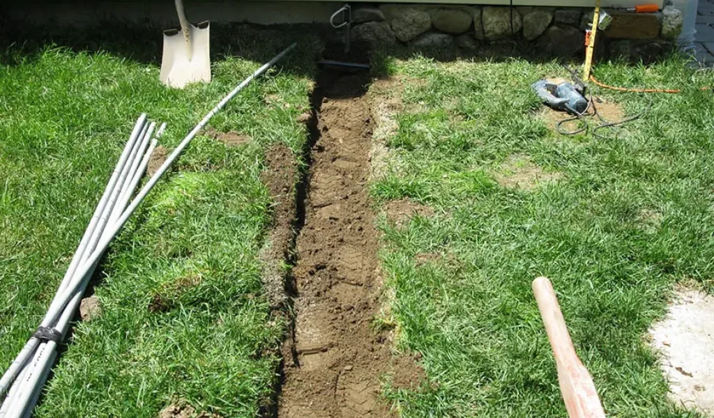 Lawn sprinkler system trenching with exposed irrigation pipes showing proper pipe placement to prevent leaks in Raleigh, NC