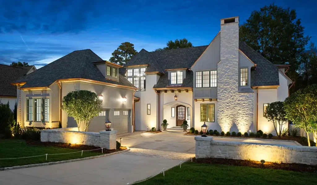 Luxury home in Raleigh, NC with architectural outdoor lighting highlighting stone walls, entryway, and landscaping at night
