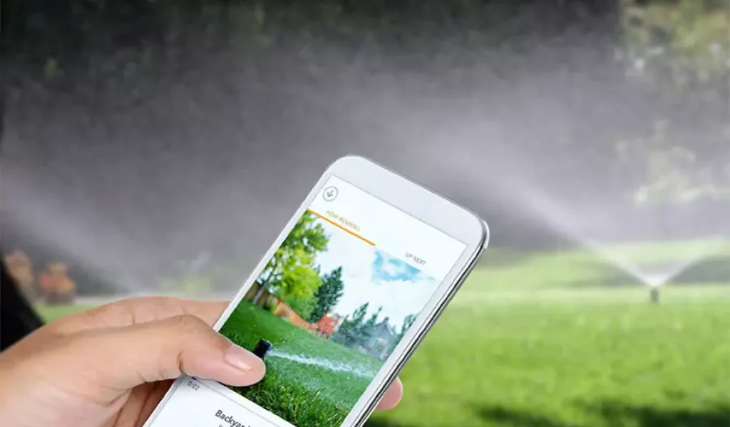 Person using a smartphone to control a smart irrigation system, showcasing the convenience of modern lawn care technology.