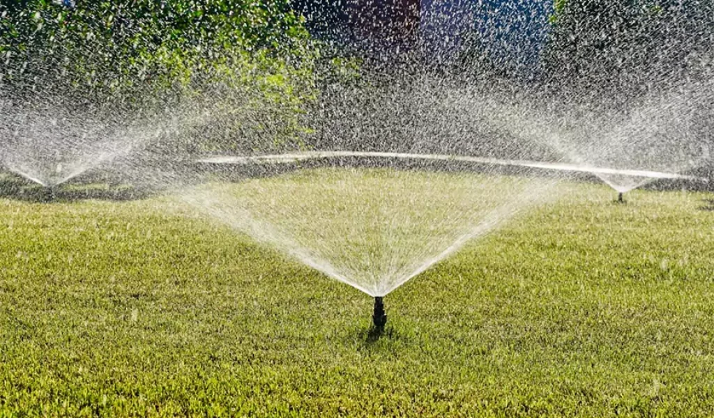 Lawn sprinkler system spraying water across green grass for irrigation and landscape maintenance in Raleigh, NC