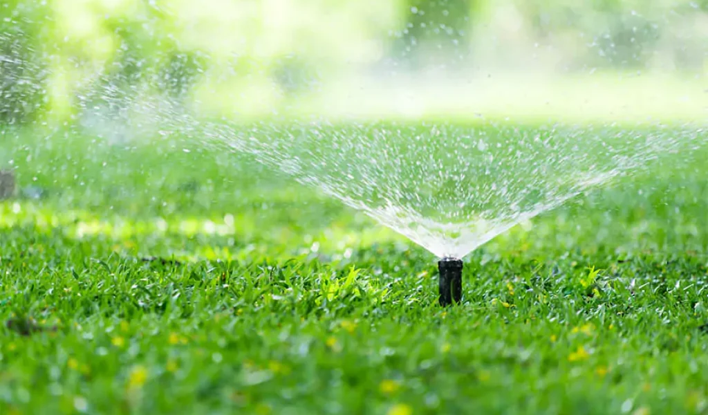 In a green lawn installed sprinkler system that is watering